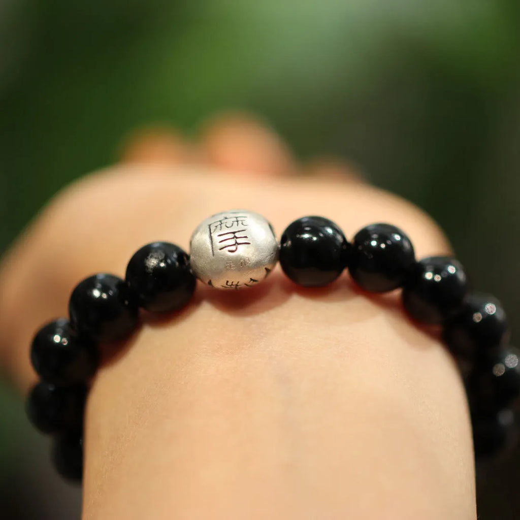 Close-up of a women's black agate bracelet with a sterling silver clasp on an alloy chain.