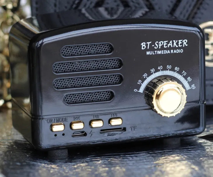 Vintage wood effect portable Bluetooth speaker in pink, black, and wood grain colours on a wooden table.