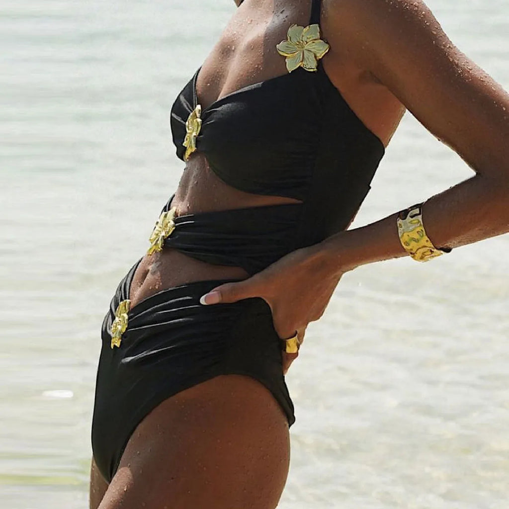 Women's black hollow-out tube top one-piece swimsuit with matching high-waist short skirt laid flat.
