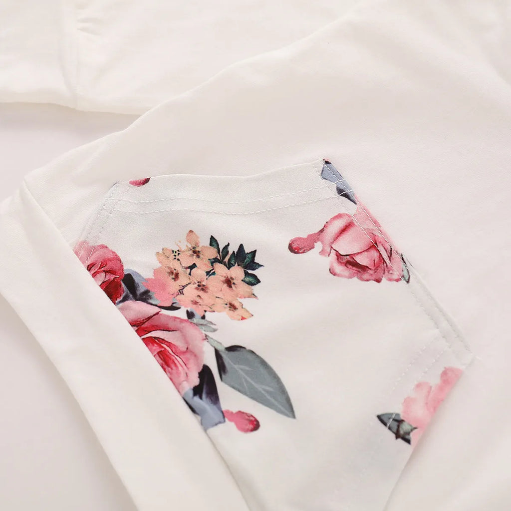 White cotton hooded pantsuit for a baby girl on a hanger, showing long sleeves and full-length trousers.
