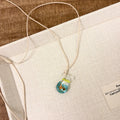 Women's joker pendant necklace with coloured glaze charm on a cotton and linen clavicle chain.