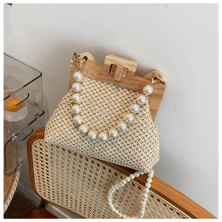Women's woven straw shoulder bag with pearl chain strap in beige, showing internal organiser pockets.