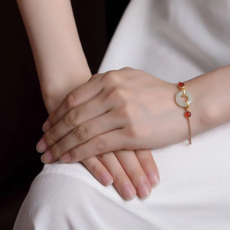 Gold-coloured women's bracelet with a silver and jade peace buckle on an adjustable chain.