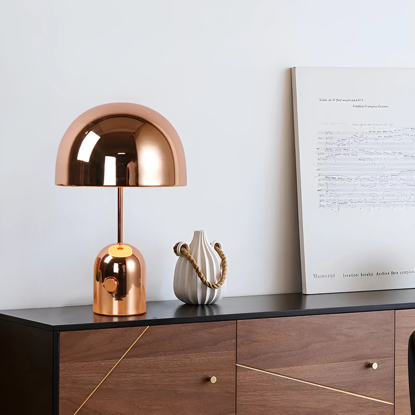 Modern mushroom table lamp with metal base in rose gold finish on a wooden table.