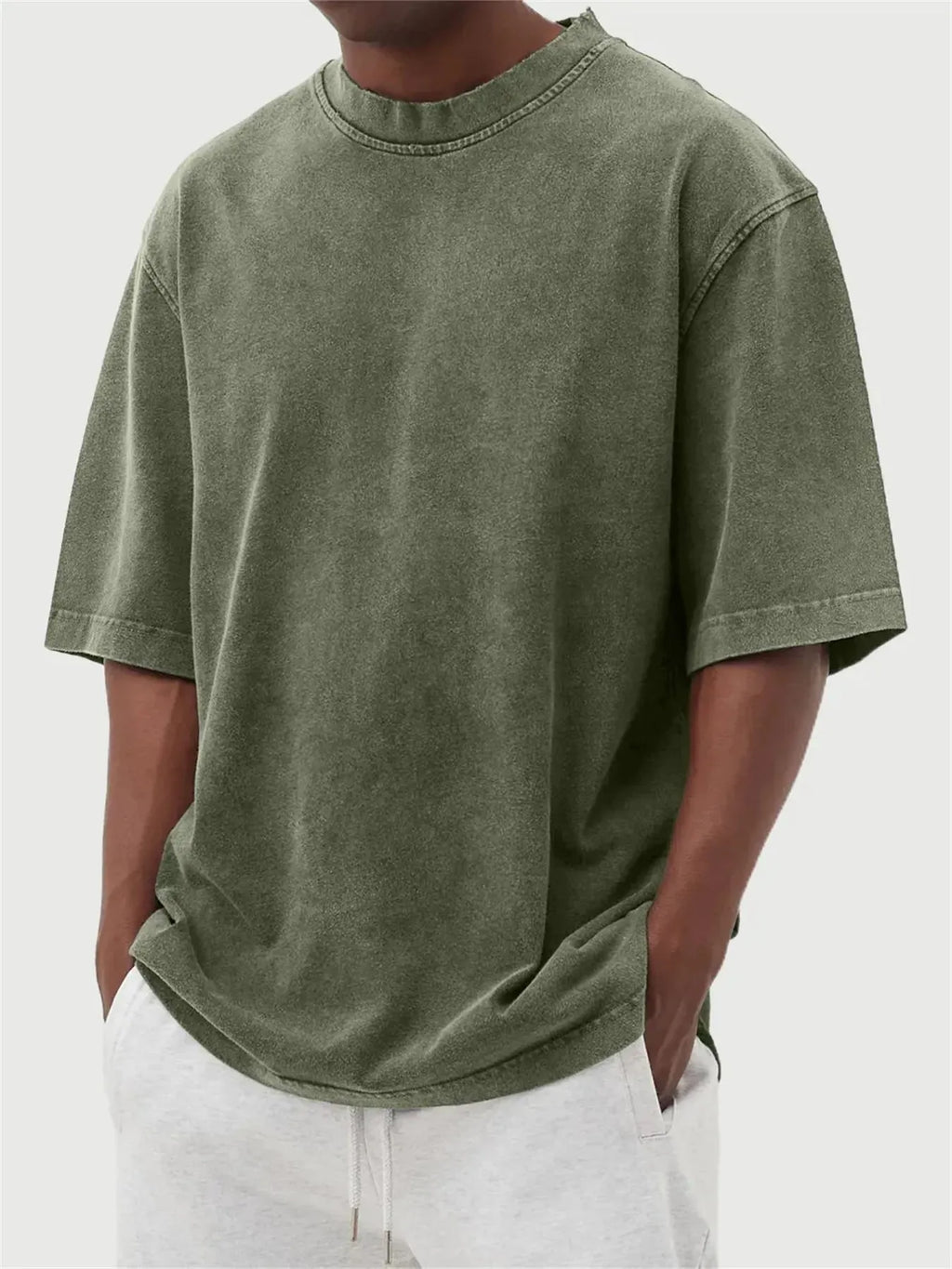Man wearing a loose-fit, distressed army green pullover T-shirt with half sleeves.