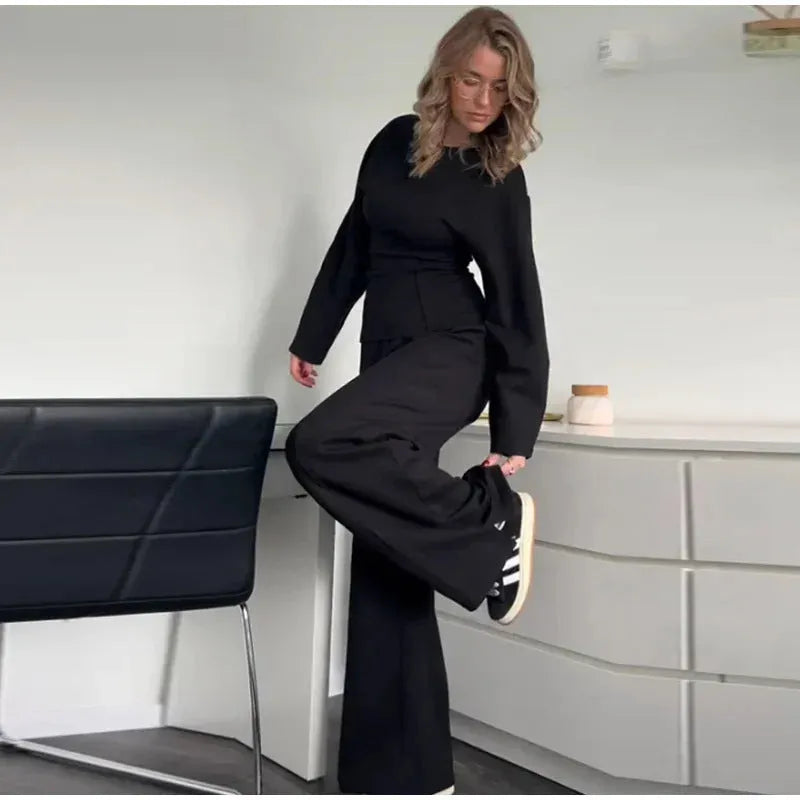 Women's black polar fleece suit set with long sleeve pleated top and wide leg trousers on a hanger.