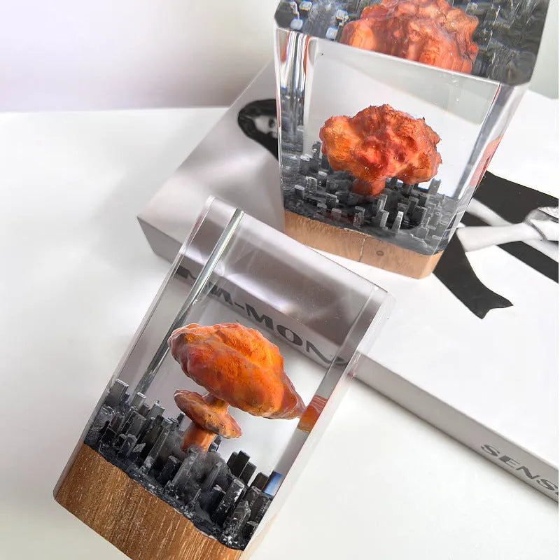 Small atomic bomb mushroom cloud shaped resin night lamp decoration in two colour variants on a dark surface.