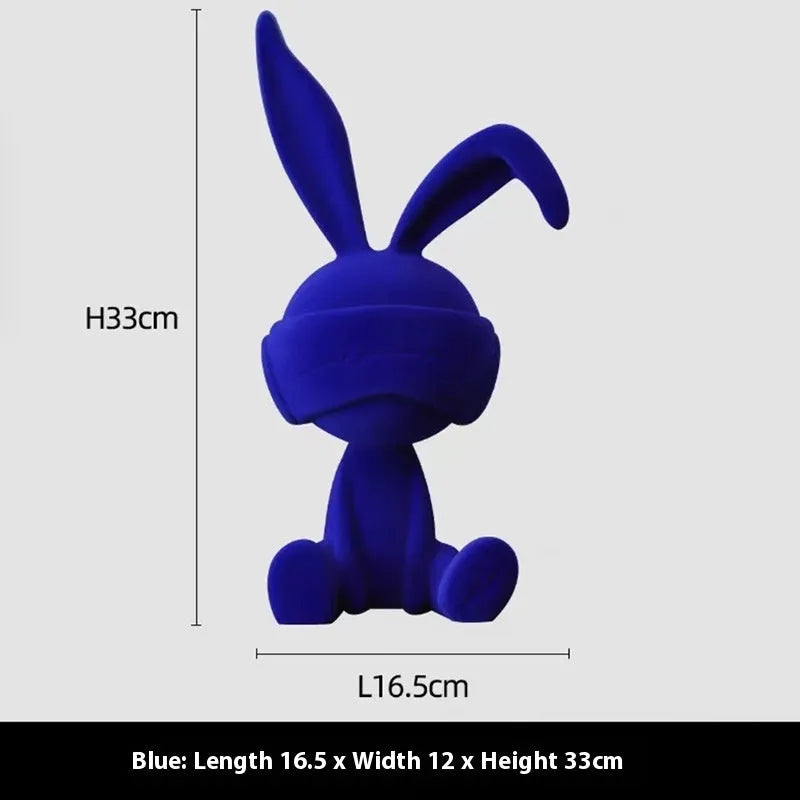 Green suede blindfold rabbit resin ornament seated on a table