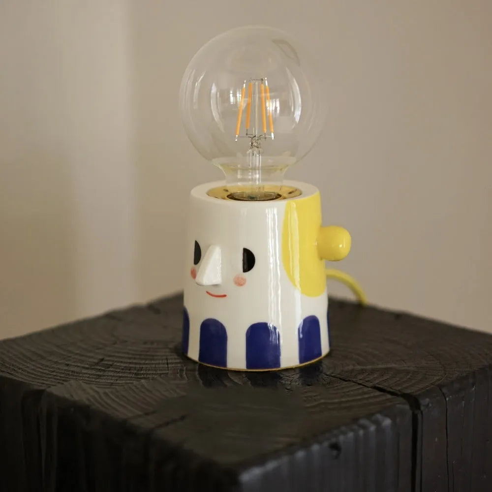 Handmade white ceramic table lamp with a creative ball headlight design on a wooden surface.