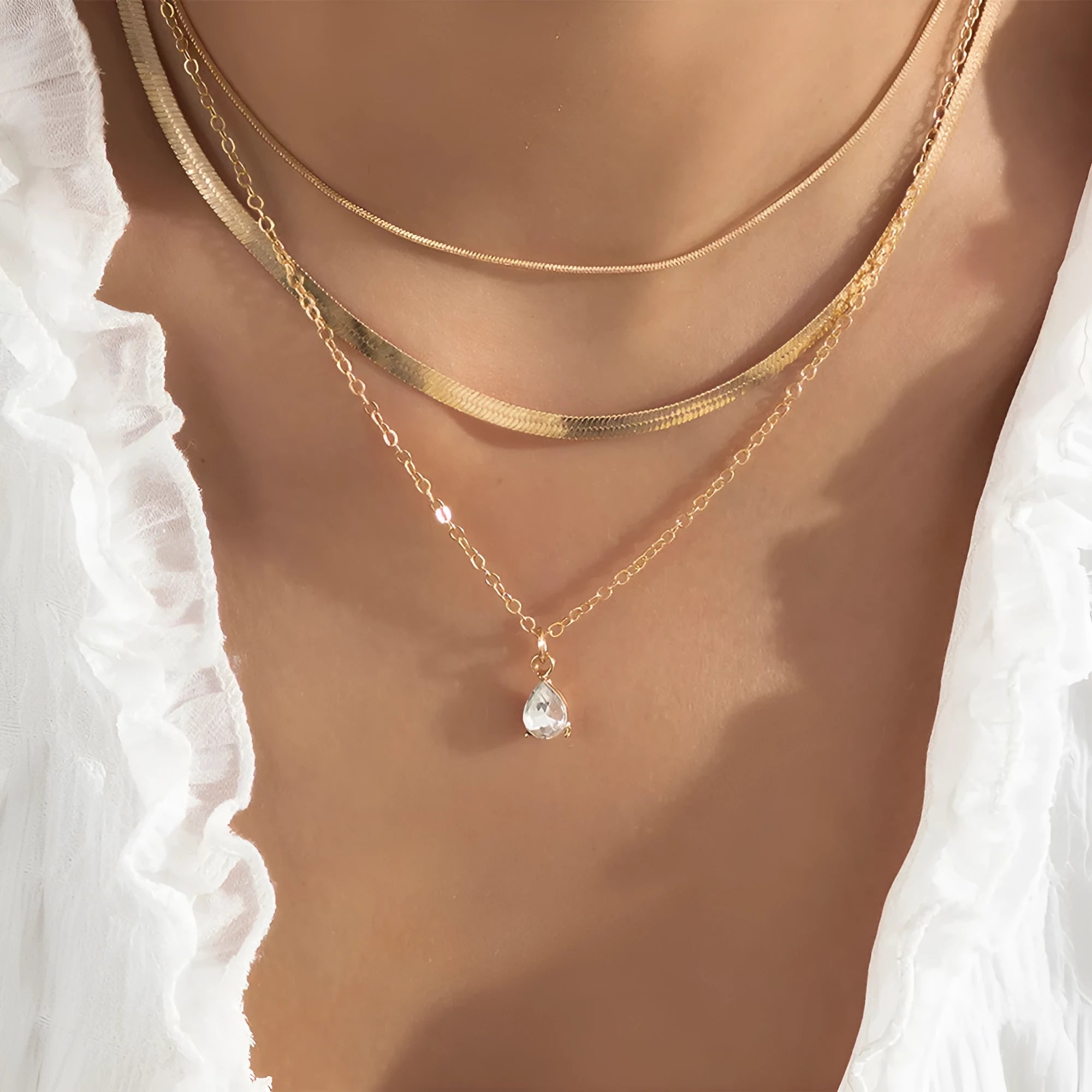 Gold and silver water drop shape alloy pendant necklace with electroplated finish on white background