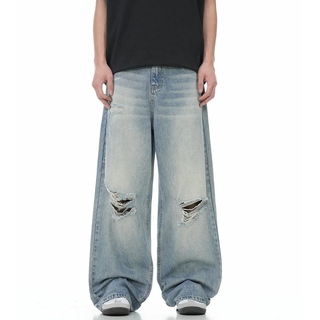 Blue men's straight-leg ripped jeans on a neutral background, showing zipper fly and cotton blend fabric texture.