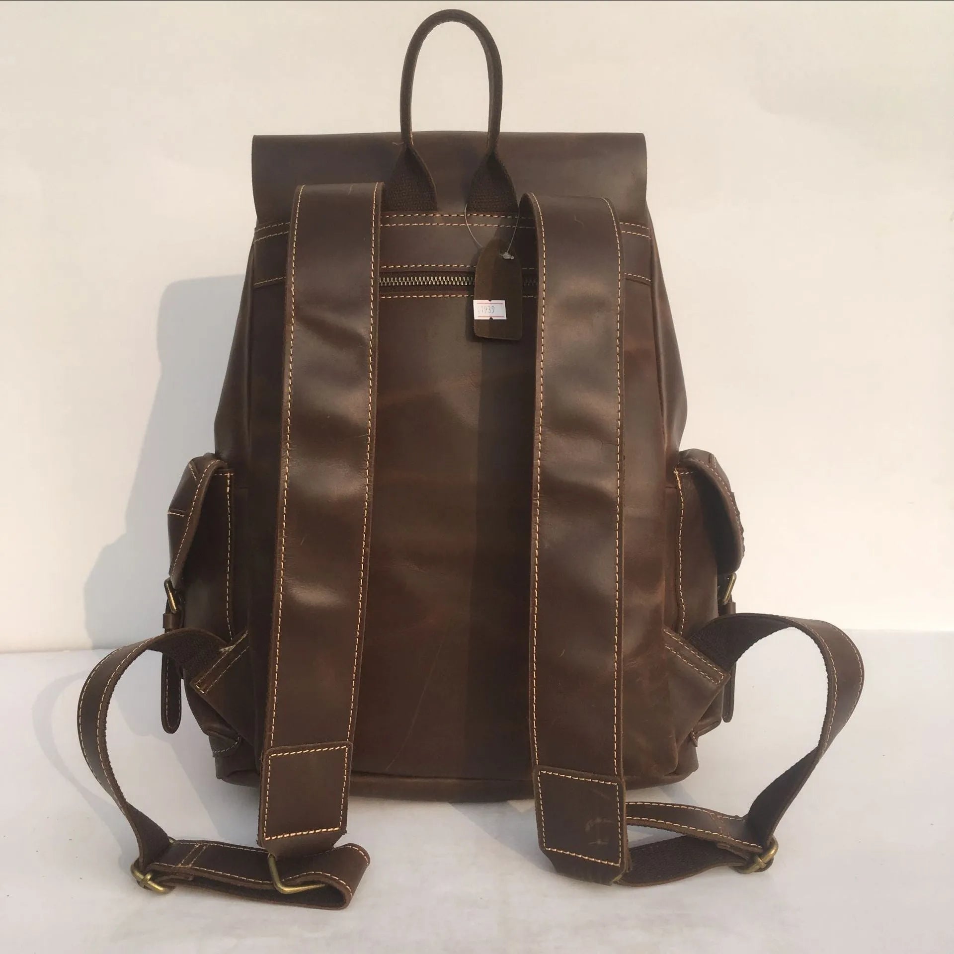 Brown men's leather backpack showing genuine cowhide material and integrated air pillow shoulder straps.