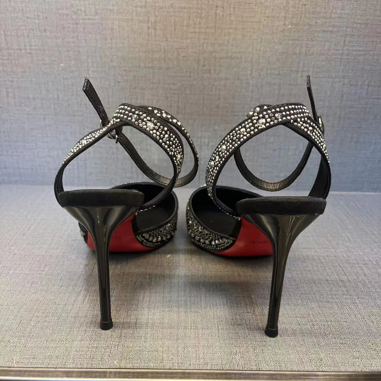 A pair of women's black hollow high heels with a red sole, stiletto heel, and pointed toe.