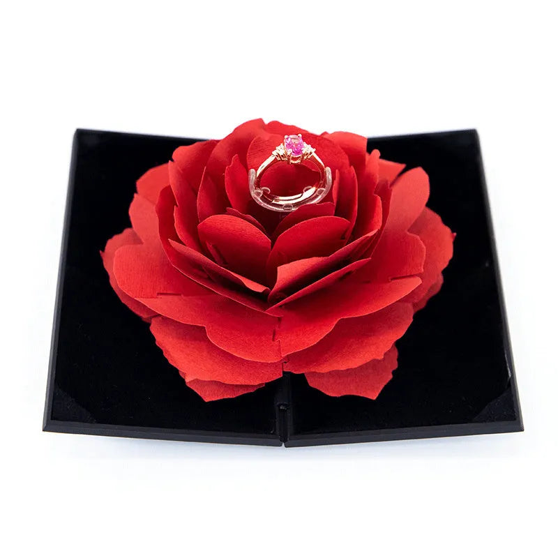 Red plastic heart-shaped rotating ring box with rose decoration inside white storage case
