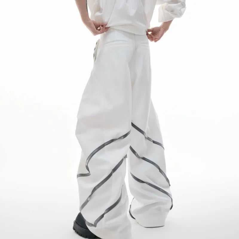 Men's black trousers with metal rivet stripes and pleated detail on the leg.