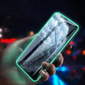 Luminous full cover tempered glass screen protector for iPhone glowing in dark on a phone.