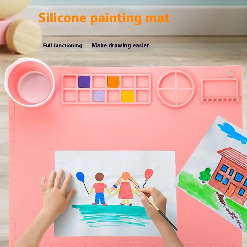 Light blue silicone painting mat measuring 50 by 40 centimetres on a wooden table.