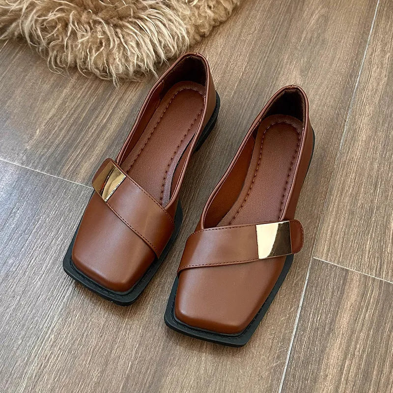 Women's beige square-toe flat shoes with a metal buckle and low rubber sole.