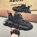 Men's black low-top sneakers with mesh upper, thick rubber sole, and round toe lace-up design.