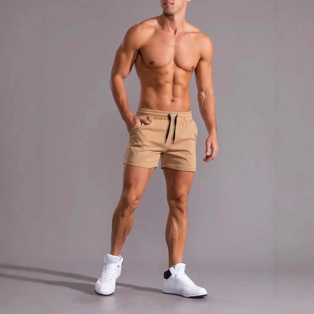 Three pairs of men's solid-colour drawstring shorts in black, khaki, and light brown laid flat.