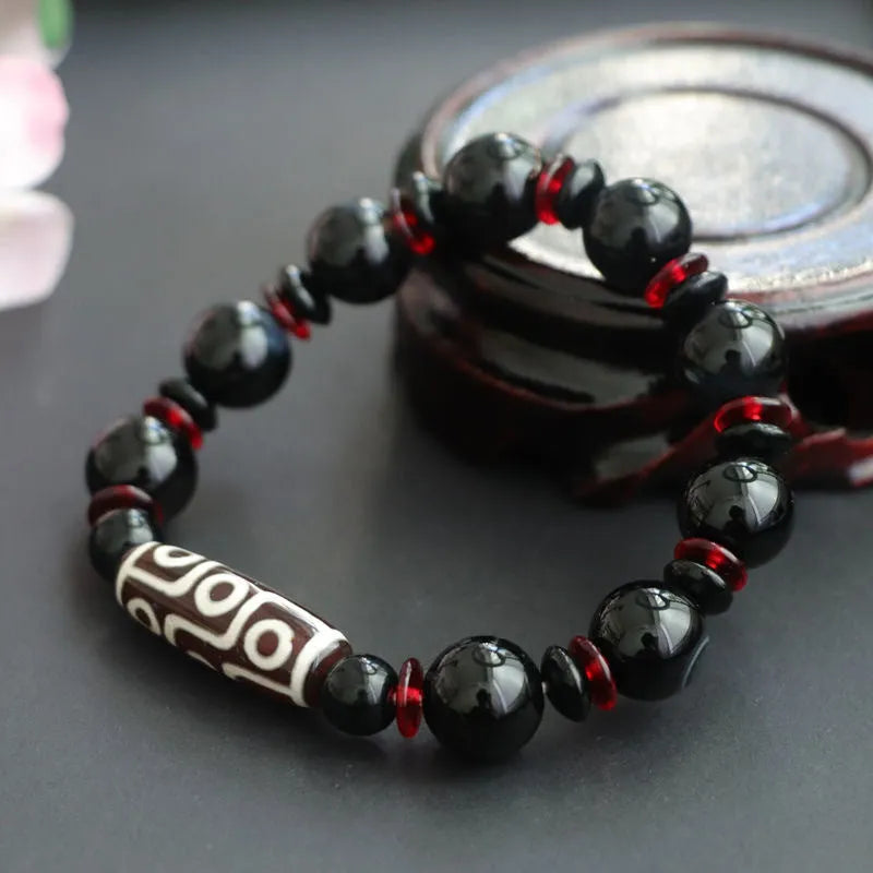 Hand-woven black agate Dzi bead bracelet with chalcedony detail on a wrist.