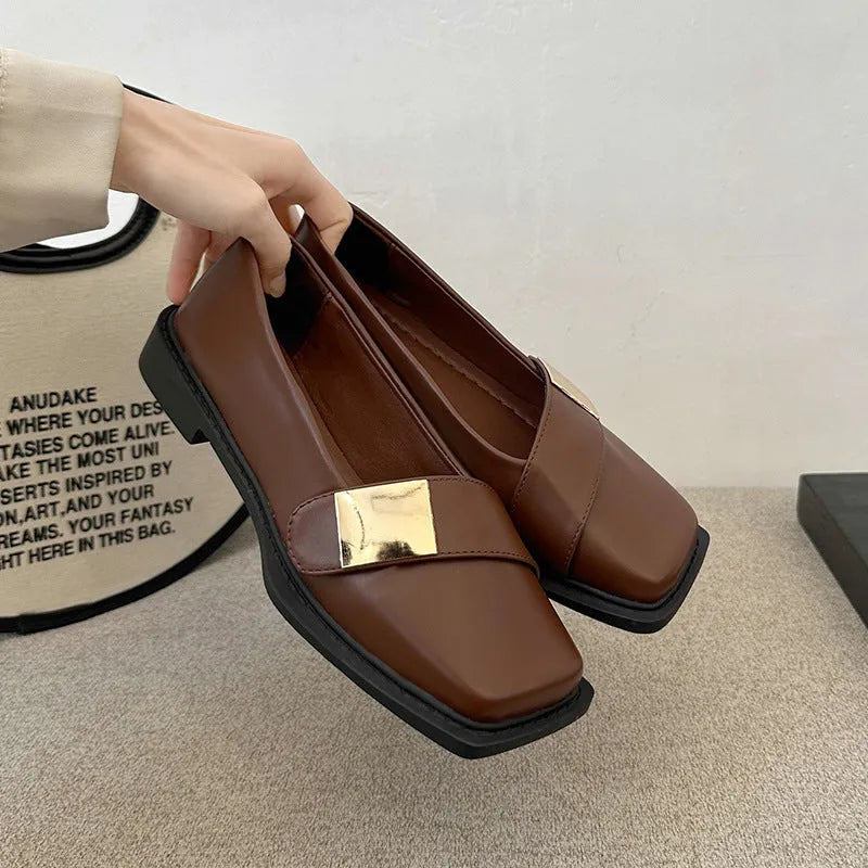 Women's beige square-toe flat shoes with a metal buckle and low rubber sole.