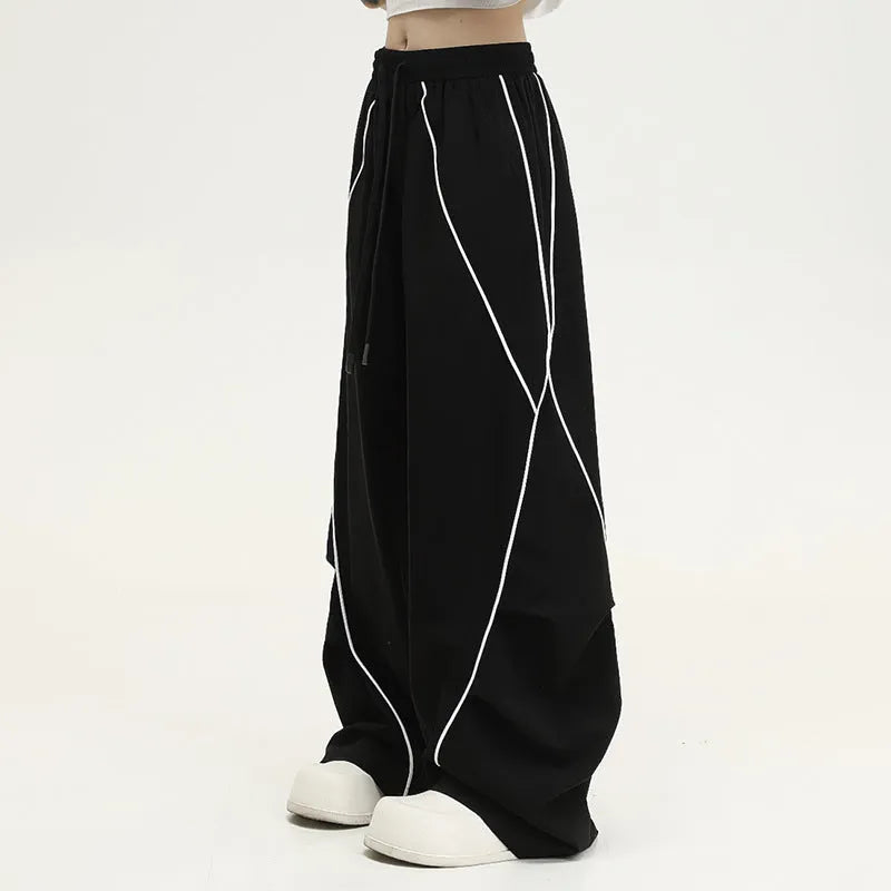 Black striped pleated wide-leg hip hop trousers laid flat, showing loose fit and mid waist.