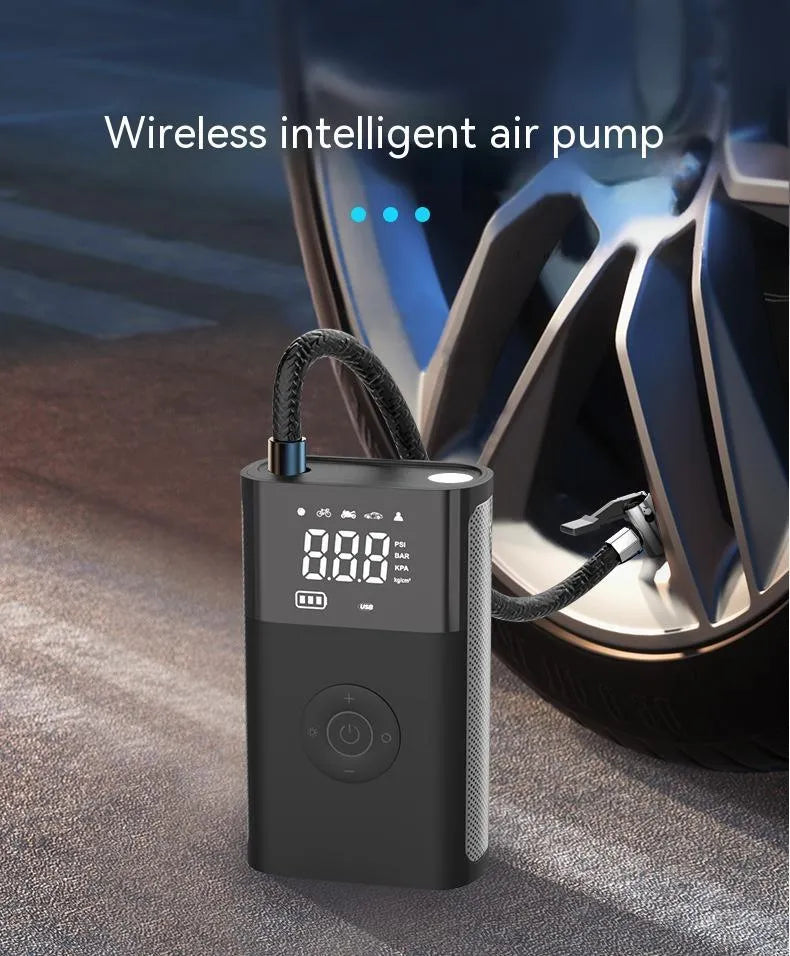 Black handheld wireless digital tyre inflator with LCD screen, LED light and multiple nozzle attachments on a table.