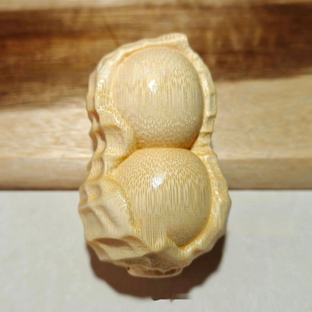 Solid natural bamboo carving of a peanut ornament on a wooden surface