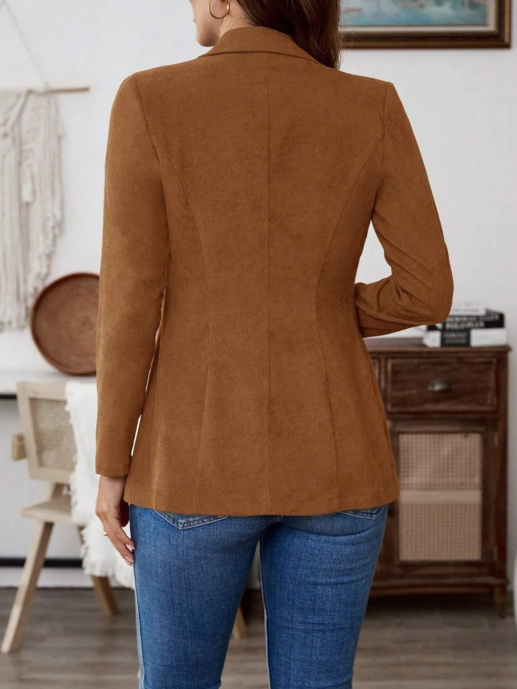 A brown men's single-breasted lapel suit coat with long sleeves on a hanger.