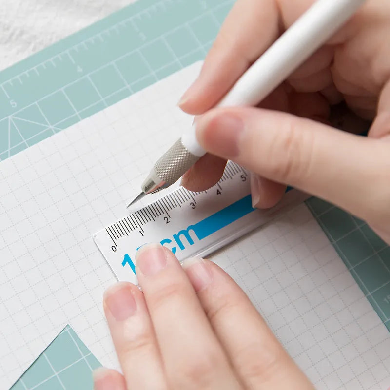 Art pen knife cutting board set in blue, showing plastic backing board with ruler, metal blade, and sharpener.