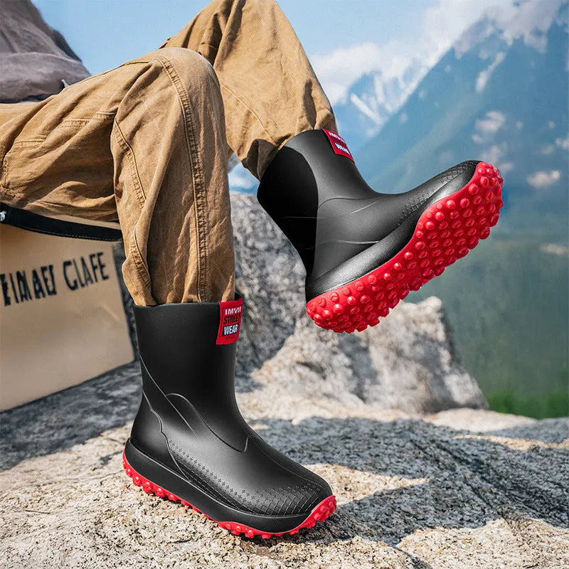 Men's black and red PVC rain boot with a round toe and non-slip plastic sole on a wet surface.