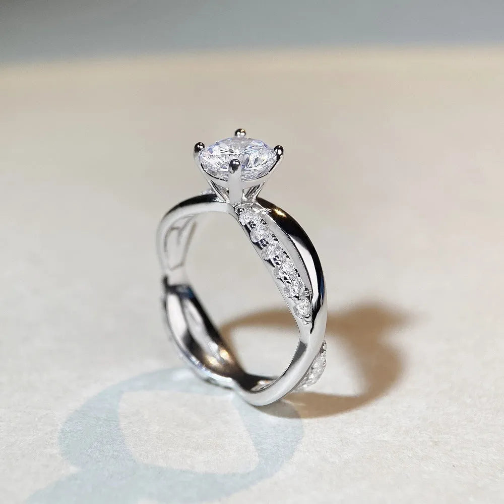 Geometric silver ring with a 1 karat moissanite stone in a four-claw setting and twisted arm band.