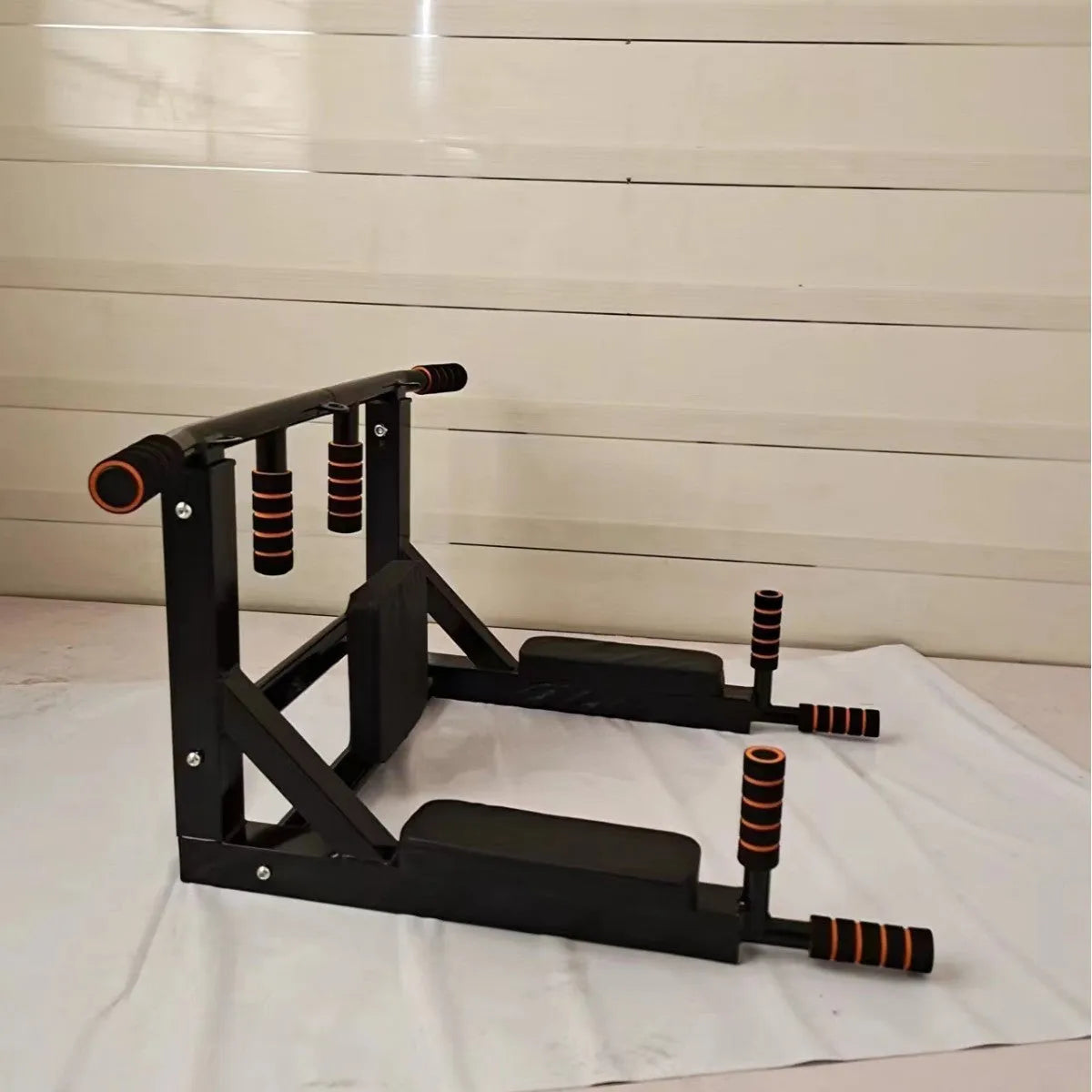 Black wall-mounted steel fitness rack with a sandbag holder and parallel pull-up bars.