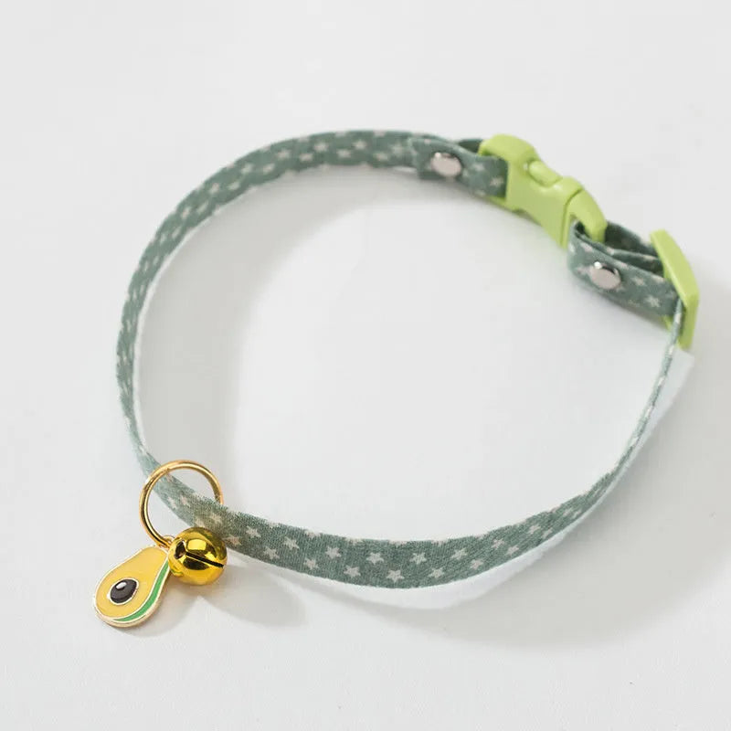 Adjustable green cat collar with a silver bell and pink bow tie on a white background.