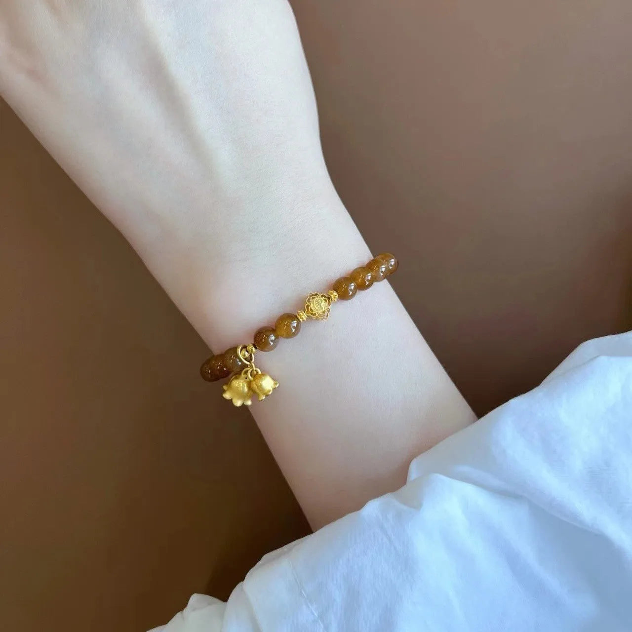 Caramel-coloured women's bracelet with electroplated beeswax finish and lily flower design.