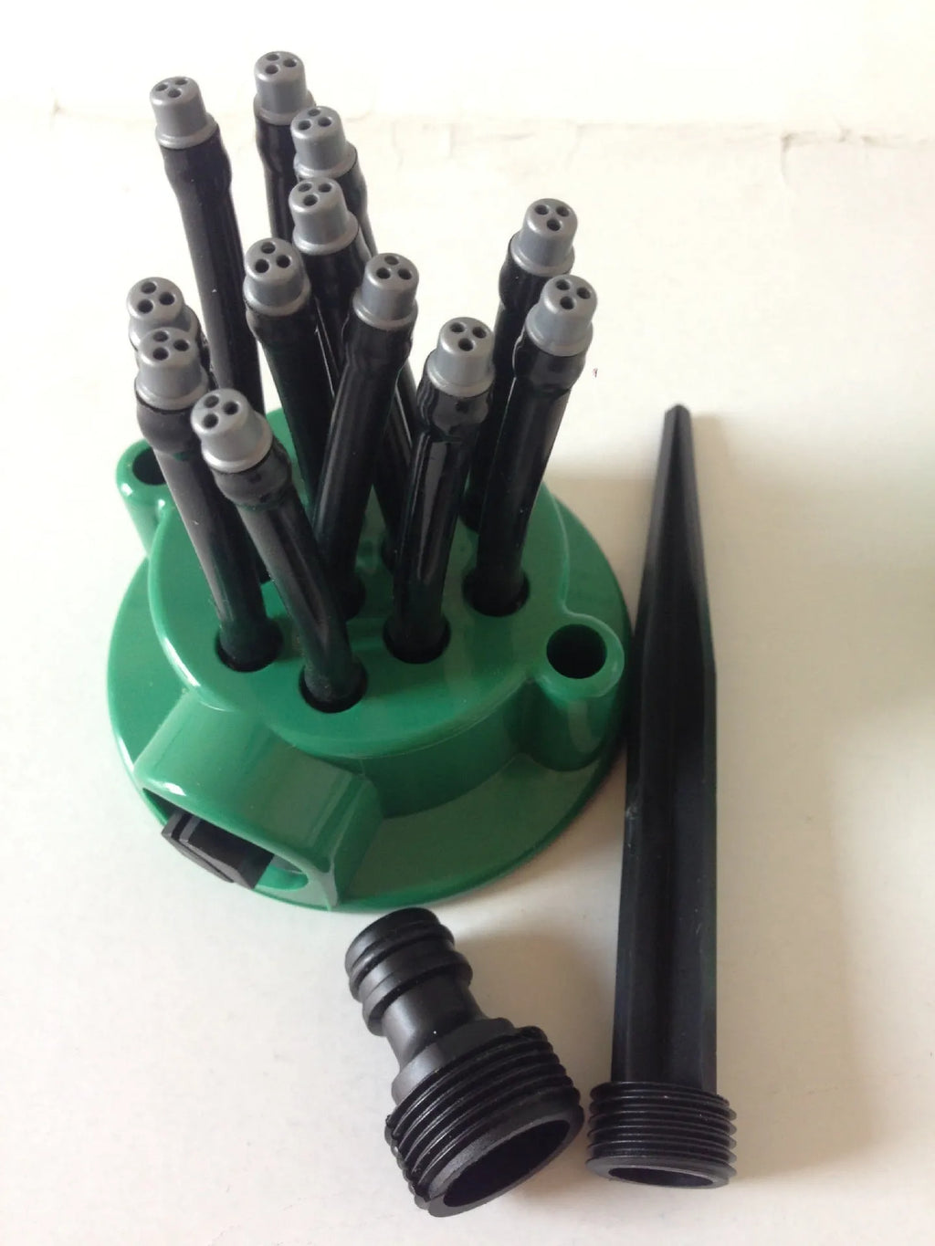 Green adjustable lawn sprinkler with bendable nozzles on 9 cm circular base