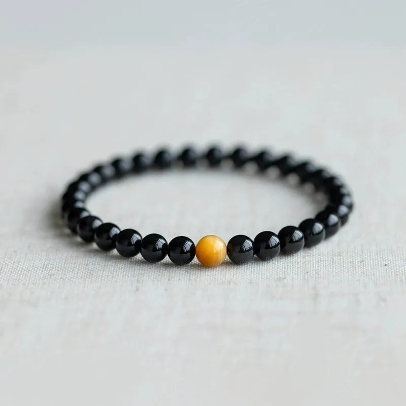 Black obsidian geometric bracelet with spherical beads on a wrist, showing unisex Korean style.