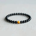 Black obsidian geometric bracelet with spherical beads on a wrist, showing unisex Korean style.