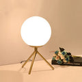 Creative desk lamp with glass shade and three-tone LED light on a desk, showing push button switch and cable.