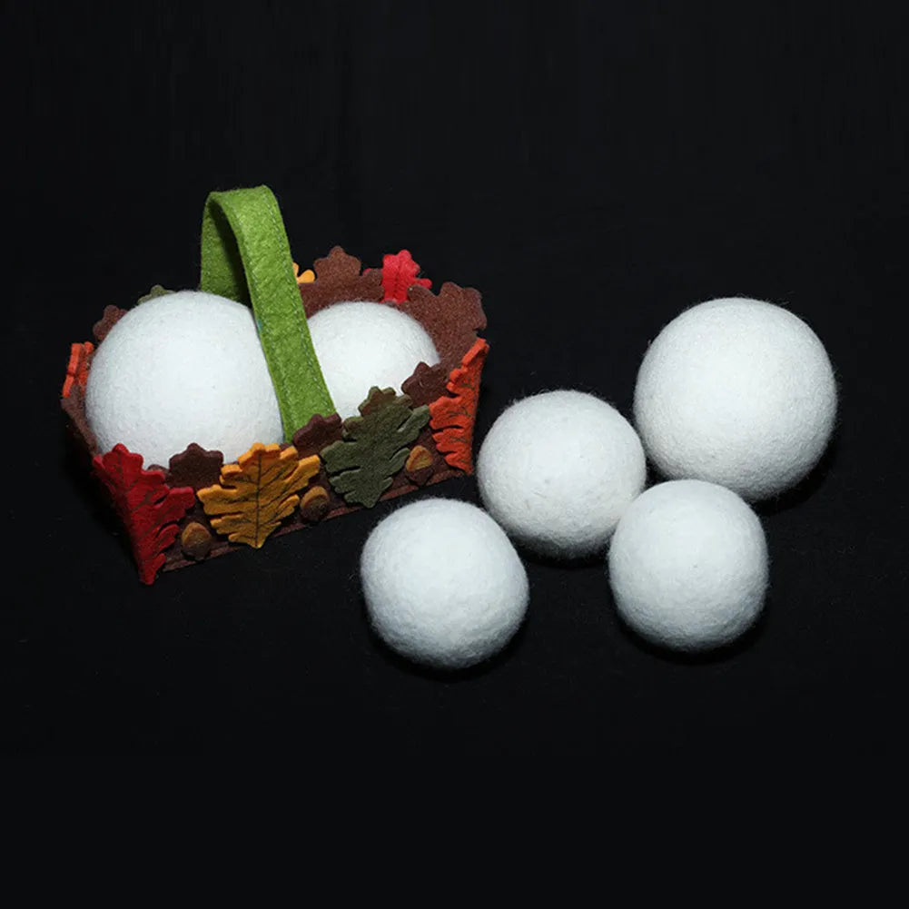 A white wool felt drying ball for laundry next to a plain cotton storage bag on a blue background.