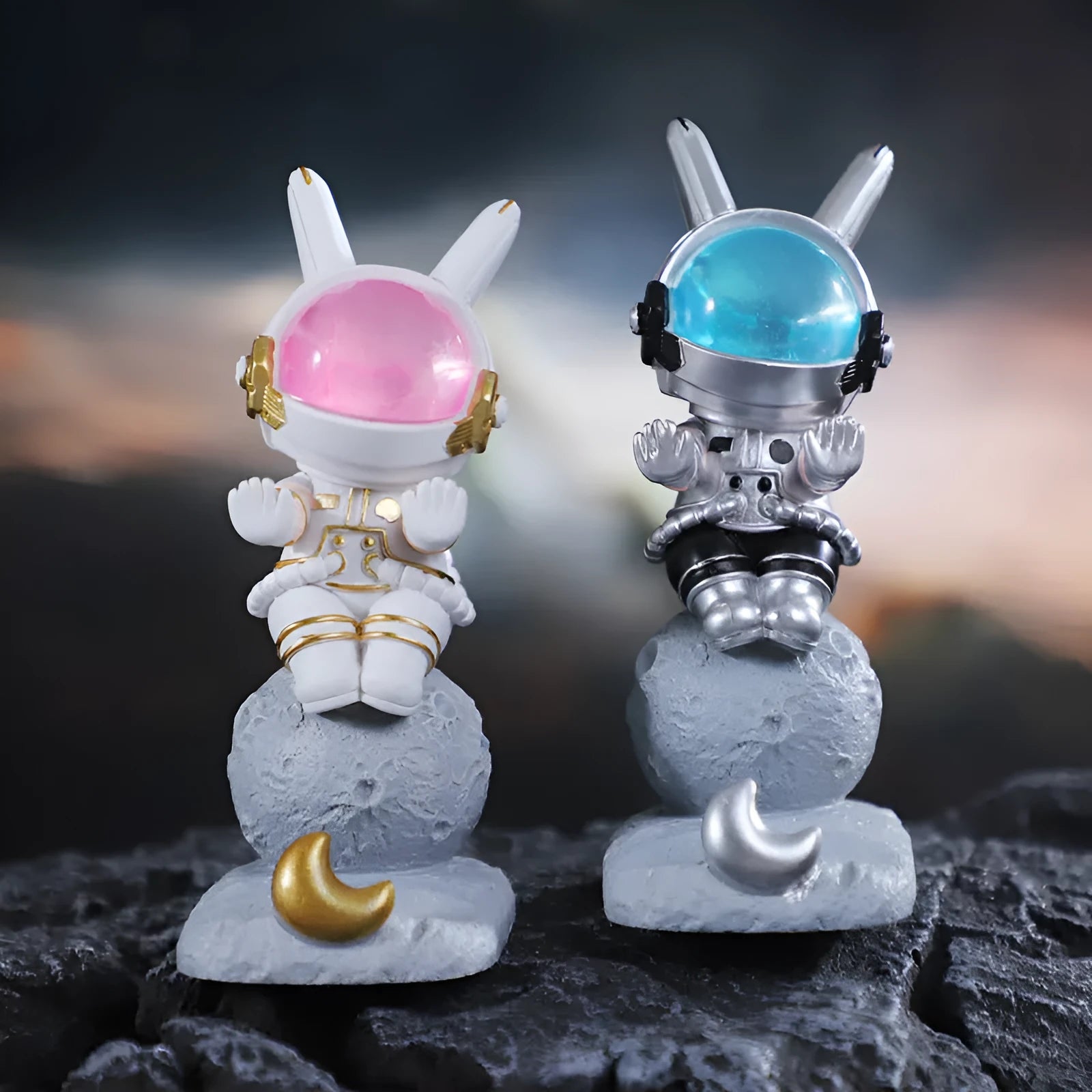 Space Rabbit resin phone stand in pink holding a smartphone on a desktop