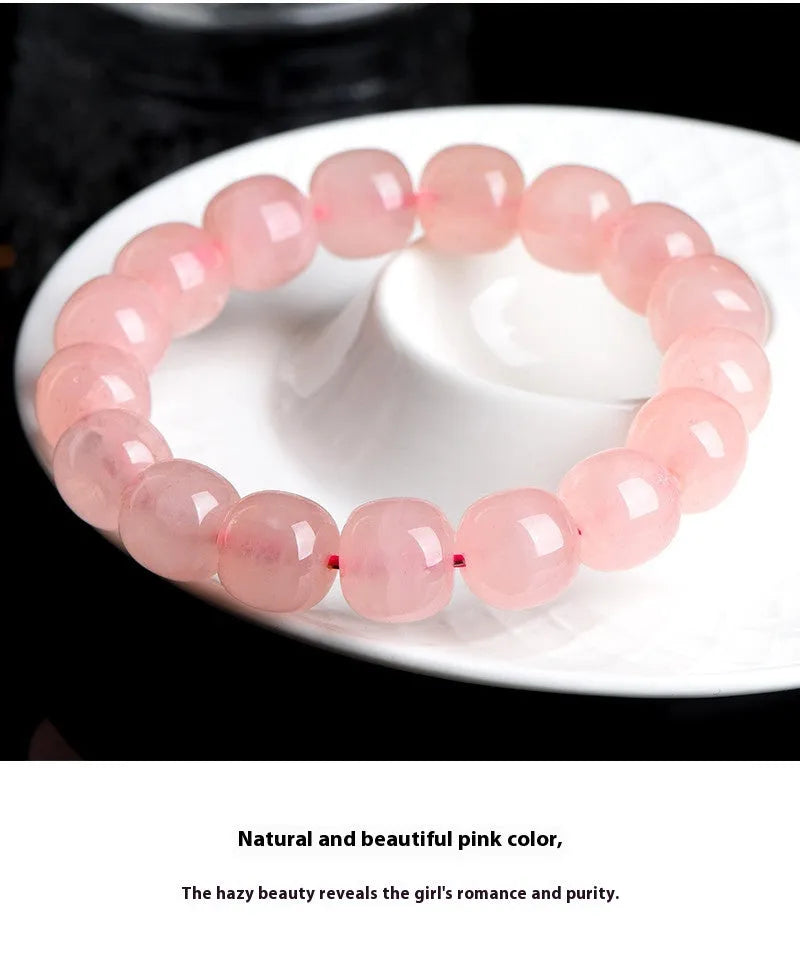 Close-up of a pink natural crystal barrel bead bracelet with geometric beads on a wrist.