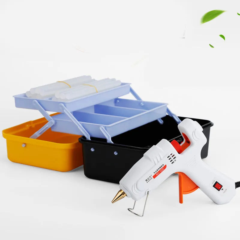 White electric hot glue gun with metal stand and glue sticks on a workbench.