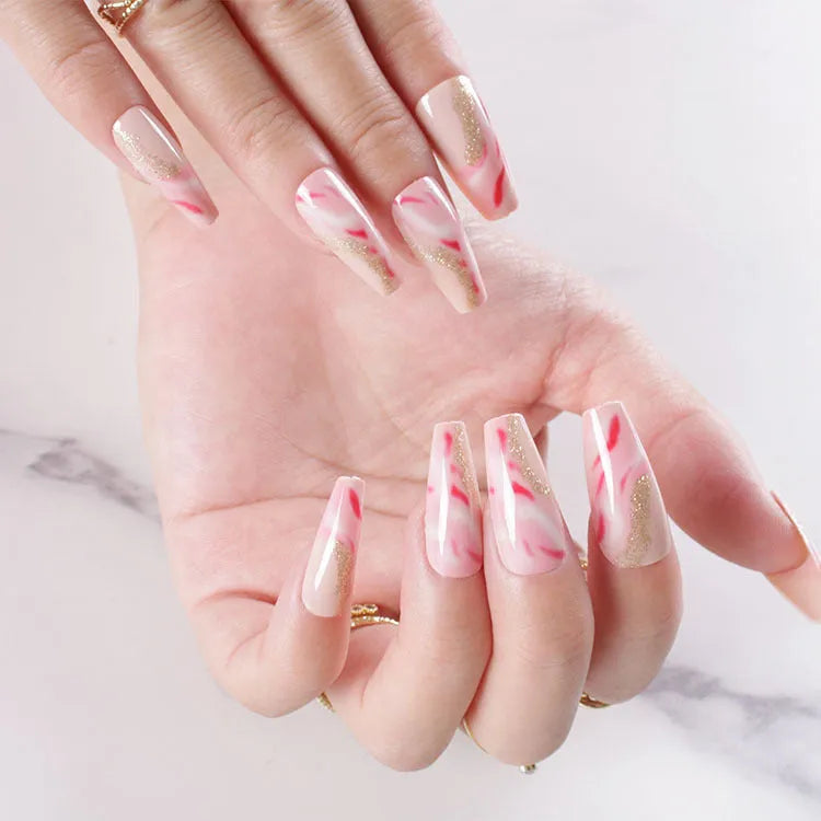 Set of pink press-on artificial nails with rose pattern, shown next to a bottle of nail glue.