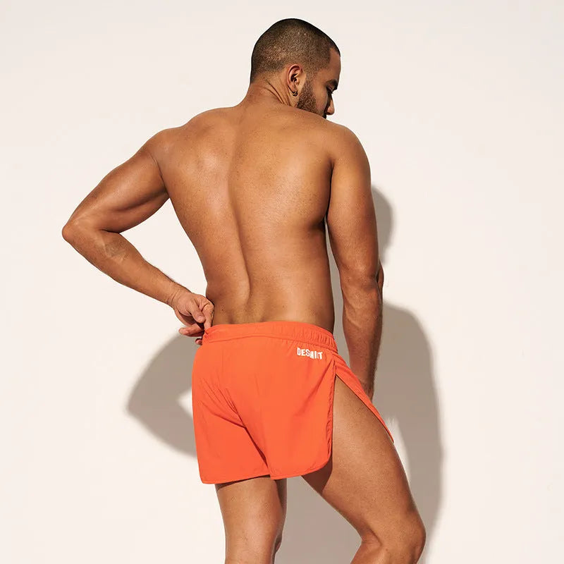 Men's loose polyester surfing shorts in orange, fluorescent green, or black on a size chart.