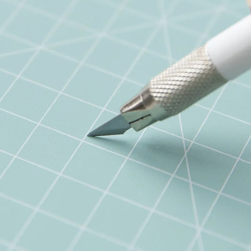 Art pen knife cutting board set in blue, showing plastic backing board with ruler, metal blade, and sharpener.