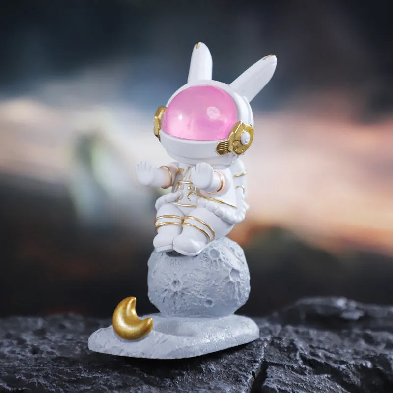Space Rabbit resin phone stand in pink holding a smartphone on a desktop
