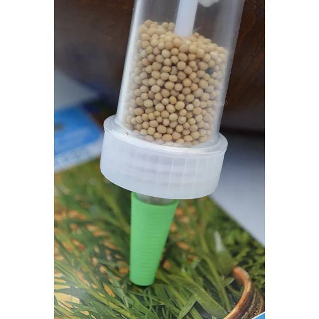 A white plastic mini seeder tool measuring 12cm long, used for planting seeds in pots and trays.