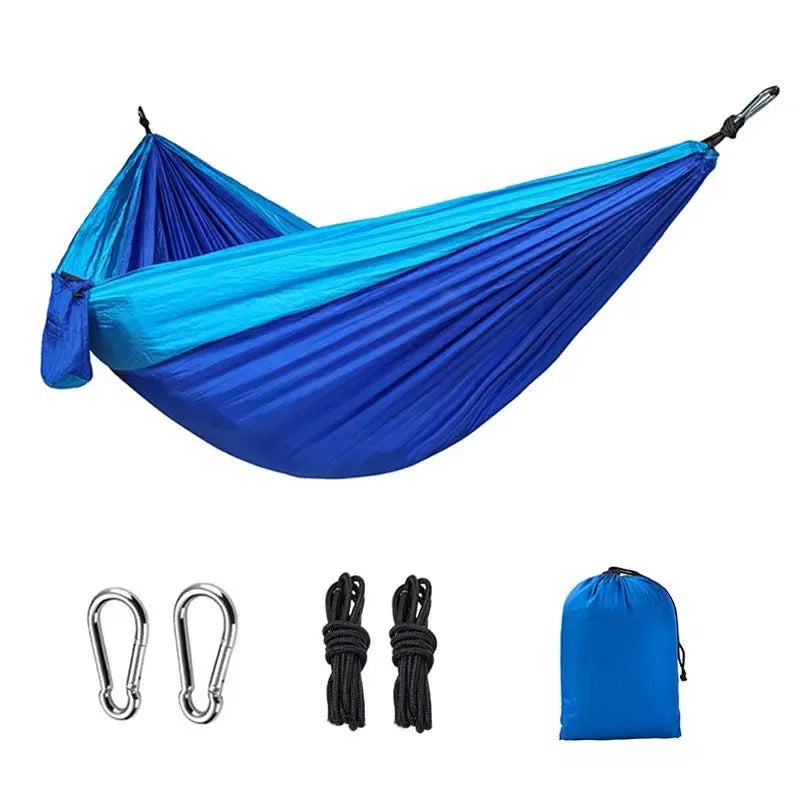 Blue nylon parachute cloth camping hammock hung between two trees outdoors